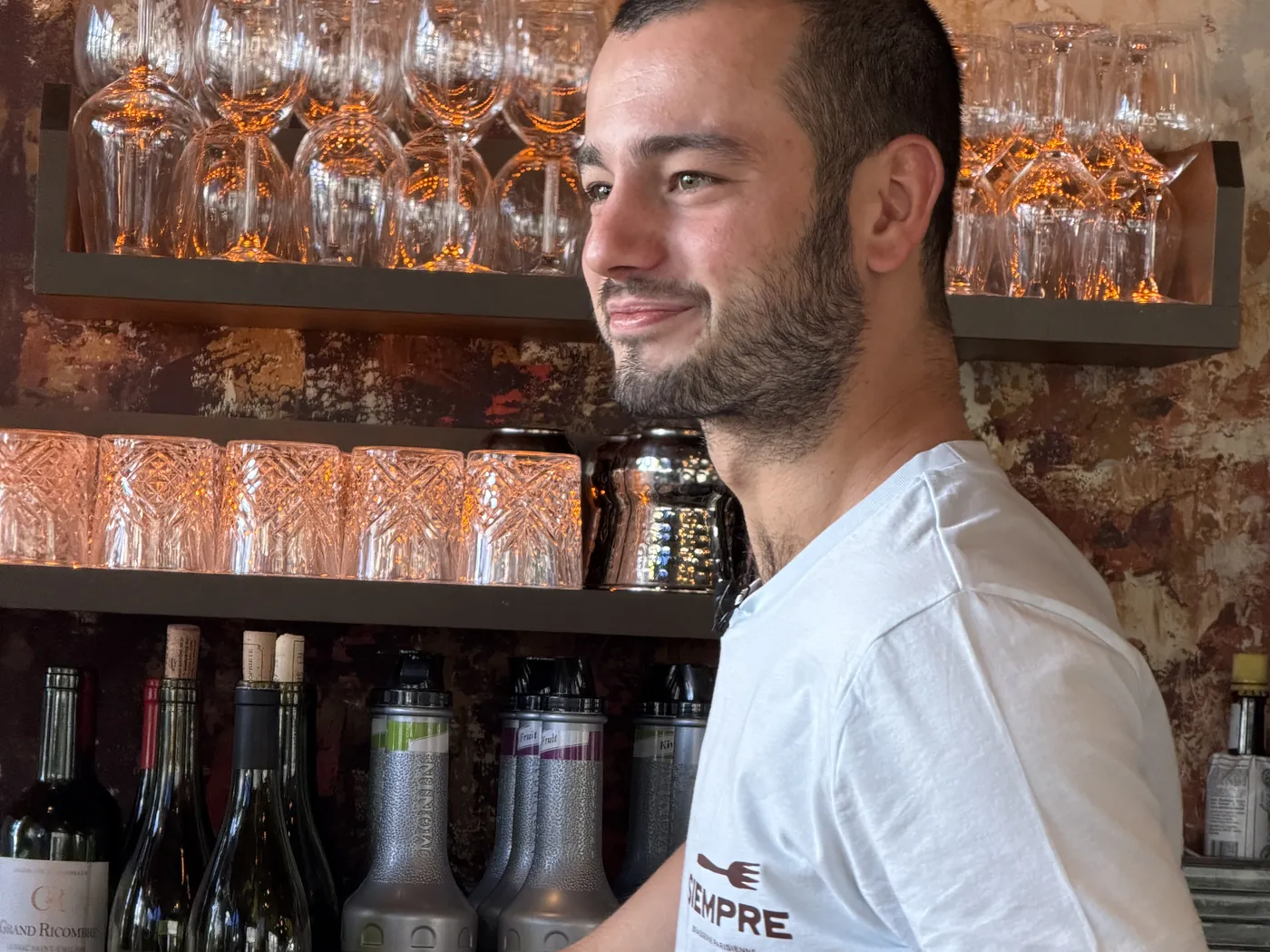 Derrière le bar du Siempre : un membre de l'équipe en t-shirt Siempre, un café à la main